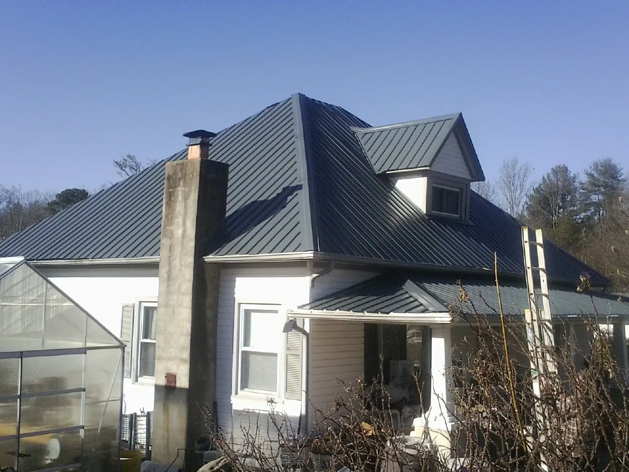 Dark blue standing seam metal roof on a white farmhouse with dormer — Slate & Tile Roof Repair by Roofing Brothers in Poland