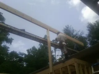 Carpenter setting a ridge beam over a new addition frame — Ice Dam Removal by Roofing Brothers in Poland