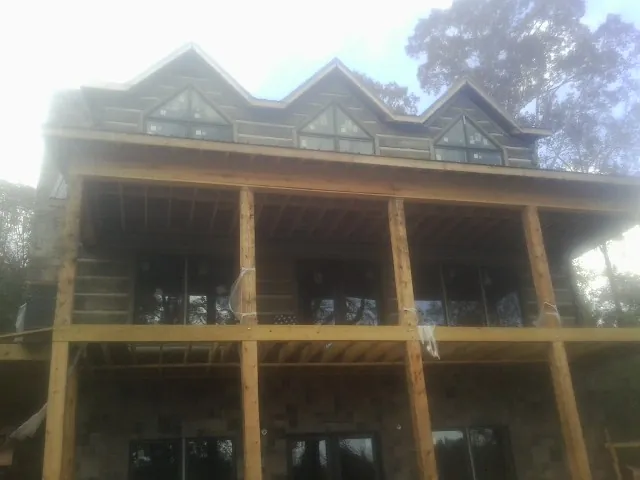 Dormers and porch framing on a large log home under construction — Roof Coating work by our crew in Poland