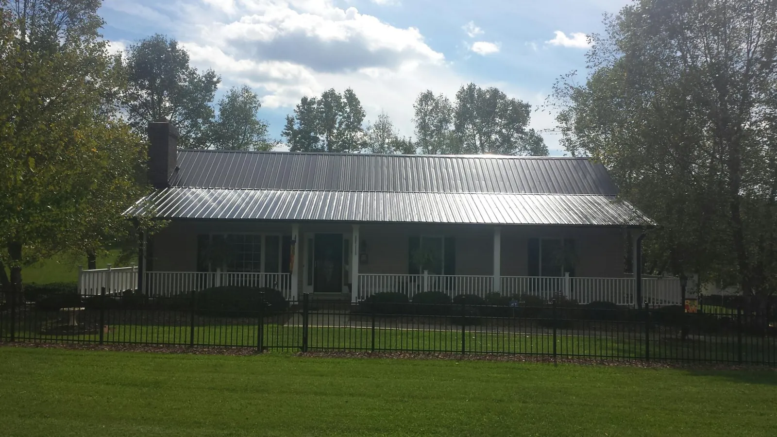 Gray metal roof on a brick ranch with a full width front porch — Gutter Guard Installation work by our crew in Poland