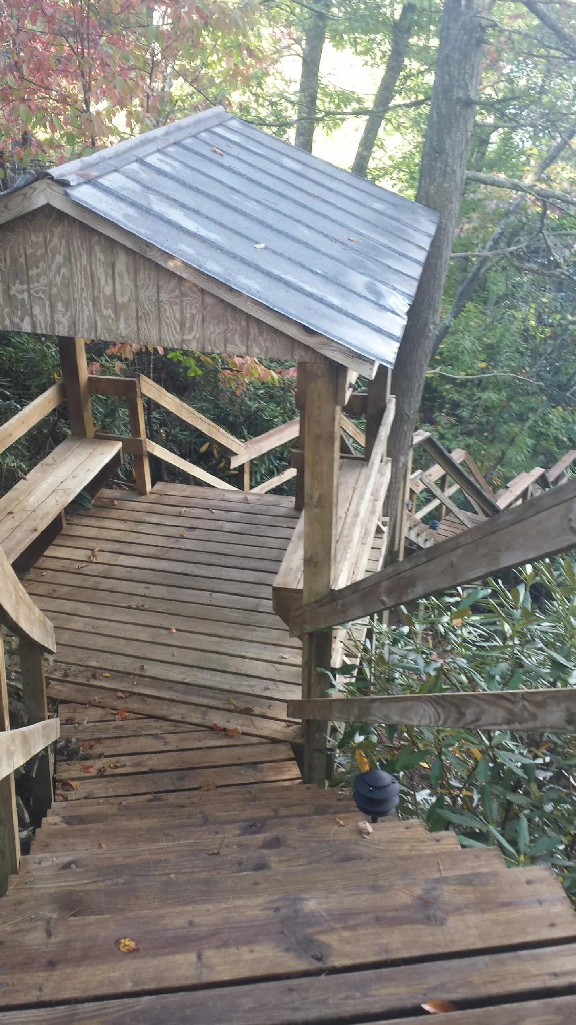 Metal roofed shelter over wooden steps on a wooded walkway — Skylight Repair & Installation work by our crew in Poland