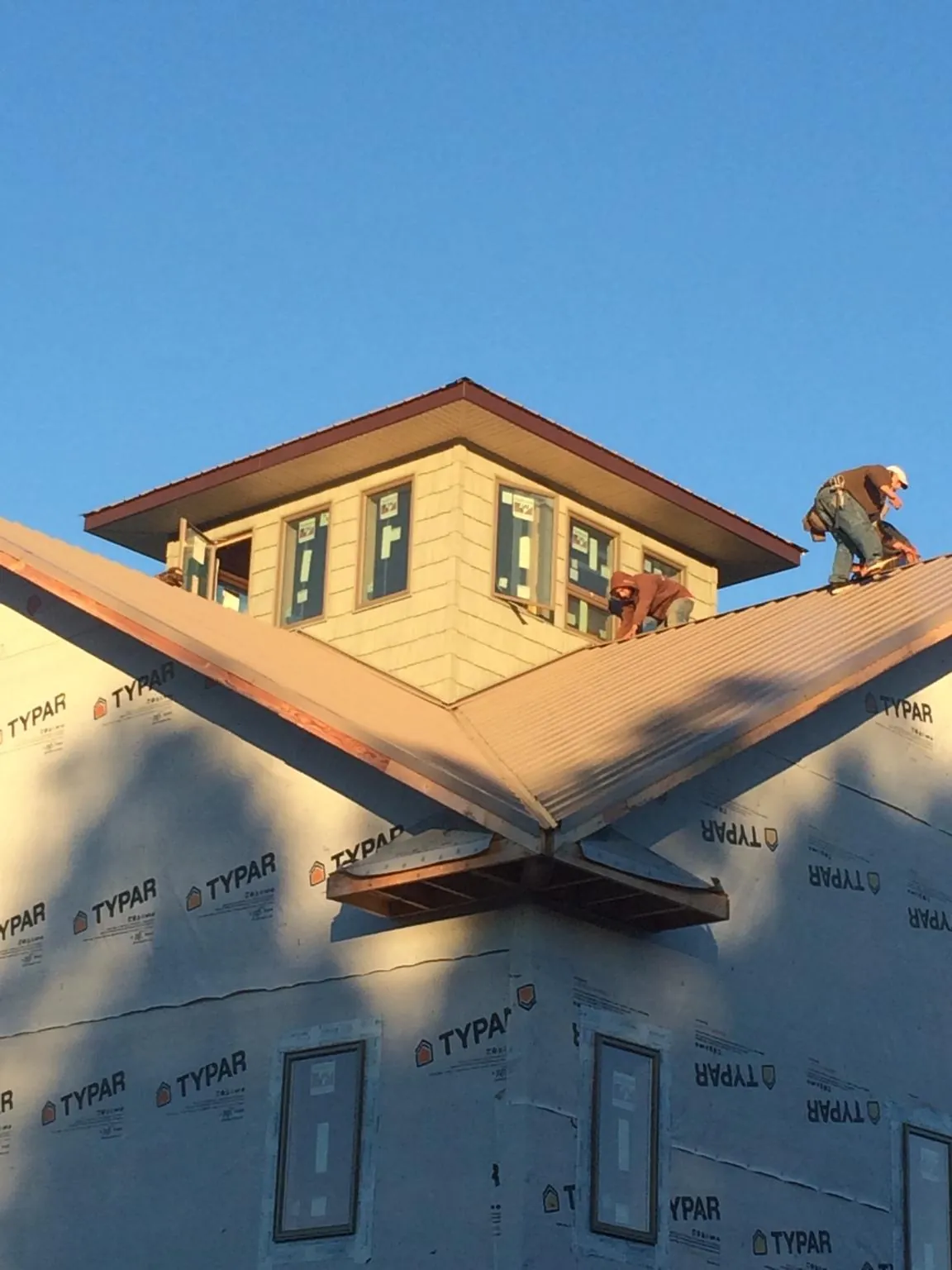 Roofers working around a rooftop cupola on a new metal roof at sunset — Roof Waterproofing in Poland by Roofing Brothers